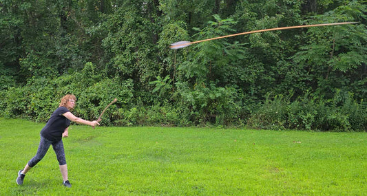 Woman demonstrating proper atlatl throwing technique with dart